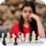 A woman supporting herself on the back of her hand looking towards chess pieces